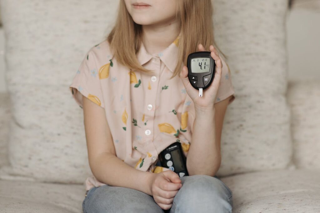 A young girl sitting at home using a glucometer to monitor her blood sugar levels, illustrating diabetes management.