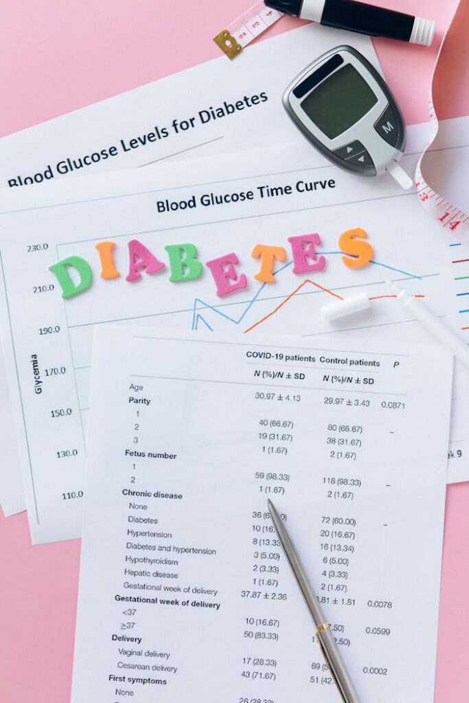 Close-up of diabetes management items: glucometer, charts, and diabetes text on pink background.